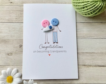 Op de afbeelding: Een witte kaart met een handgetekend plaatje van een stel dat een baby vasthoudt. De baby wordt voorgesteld door een blauwe knoop. Het stel is gemaakt van knopen, de vrouw is roze en de man is blauw. De kaart zegt "Gefeliciteerd met het grootouder worden".