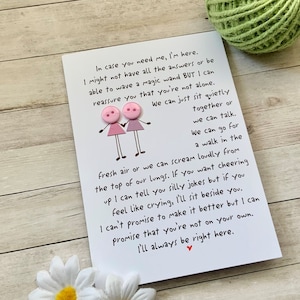 May include: A white card with pink buttons attached to it. The card has a handwritten message that reads: "In case you need me, I'm here. I might not have all the answers or be able to wave a magic wand BUT I can reassure you that you're not alone. We can just sit quietly together or we can talk. We can go for a walk in the fresh air or we can scream loudly from the top of our lungs. If you want cheering up I can tell you silly jokes but if you feel like crying, I'll sit beside you. I can't promise to make it better but I can promise that you're not on your own. I'll always be right here."