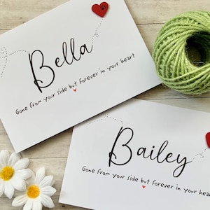 Pu&ograve; includere: Due carte bianche con testo nero e cuori rossi. Il testo sulle carte recita "Bella Gone from your side but forever in your heart" e "Bailey Gone from your side but forever in your heart".