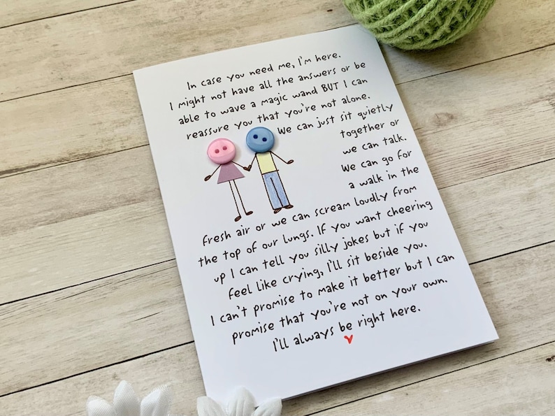 May include: A white card with a handwritten message about being there for someone. The card features two stick figures with buttons for heads. The text reads, "In case you need me, I'm here. I might not have all the answers or be able to wave a magic wand BUT I can reassure you that you're not alone. We can just sit quietly together or we can talk. We can go for a walk in the fresh air or we can scream loudly from the top of our lungs. If you want cheering up I can tell you silly jokes but if you feel like crying, I'll sit beside you. I can't promise to make it better but I can promise that you're not on your own. I'll always be right here."