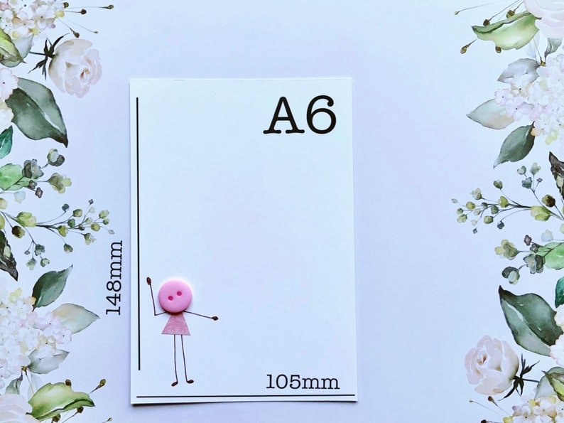 Pu&ograve; includere: Carta formato A6 con un bottone rosa e un disegno di un omino stilizzato. La carta misura 105 mm di larghezza e 148 mm di altezza.