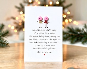 Op de afbeelding: Een witte wenskaart met twee figuren gemaakt van roze knopen en driehoekige stoffen rokjes, één goudkleurig en één rood. De tekst luidt: Friendship isn't a BIG thing, it's a million little things. Your friendship is priceless. Merry Christmas.