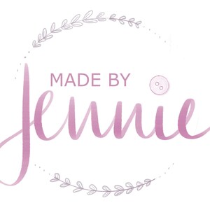 Puede incluir: Un logotipo de acuarela rosa y blanco con el texto "MADE BY Jennie" y un peque&ntilde;o bot&oacute;n gr&aacute;fico. El logotipo est&aacute; rodeado por una corona de hojas grises.