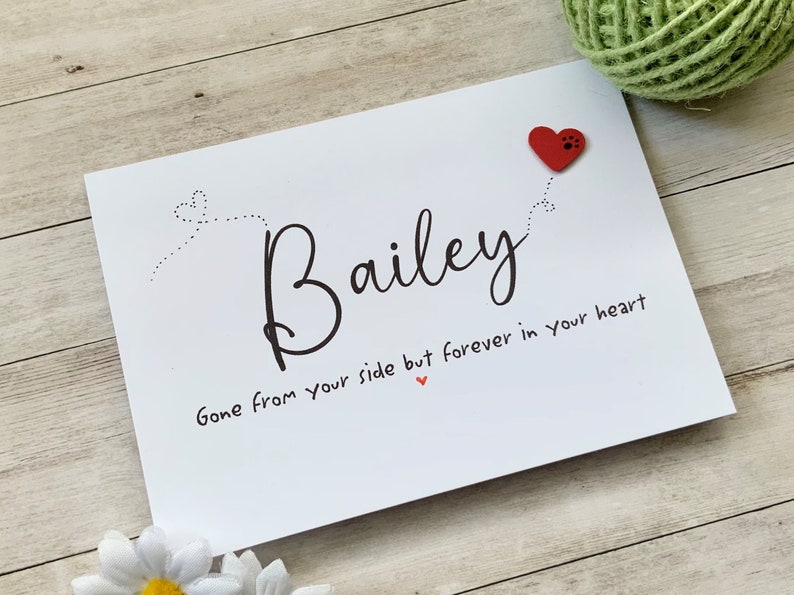 Pu&ograve; includere: Carta bianca con testo nero che recita "Bailey Gone from your side but forever in your heart" con un cuore rosso con un'impronta di zampa.