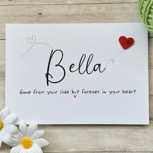 Pu&ograve; includere: Un biglietto bianco con testo nero che recita "Bella Gone from your side but forever in your heart" con un cuore rosso con un'impronta di zampa.