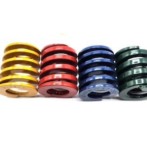 May include: Four compression springs in different colours: yellow, red, blue, and green. The springs are made of metal and have a coil design.