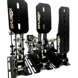 Peut inclure: Pédales de simulateur de course noires avec un cadre en métal et un système d'entraînement par chaîne. Les pédales sont étiquetées "SIMUBOX" en lettres dorées.