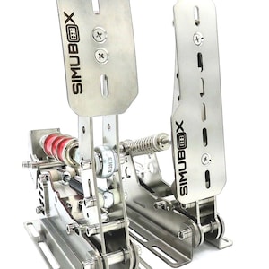 May include: A set of silver racing pedals with a chain drive system. The pedals are labeled "SIMUBOX" and feature a spring-loaded brake pedal.