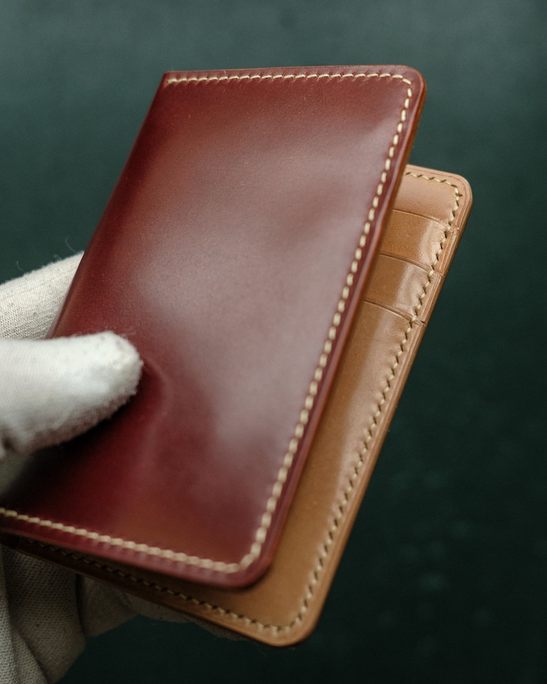 Peut inclure: Un portefeuille en cuir marron avec un int&eacute;rieur en cuir beige et des coutures blanches. Le portefeuille est ferm&eacute; et poss&egrave;de un rabat.