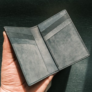 Peut inclure: Un portefeuille en cuir noir avec plusieurs fentes pour cartes et un design pliable.