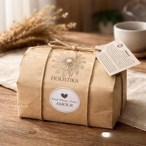 May include: A brown paper-wrapped package, secured with twine. The package features a sunflower design and the word "HOLISTIKA". A sticker with the words "Fait Main Avec AMOUR" is on the front. A tag is attached to the twine.