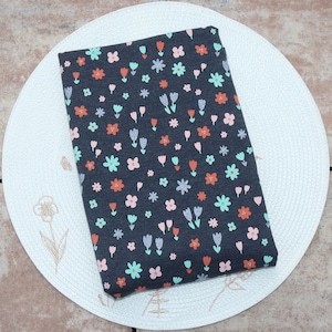 Op de afbeelding: Een donkergrijze stof met een herhalend patroon van kleine bloemen en tulpen in tinten roze, oranje en groen.