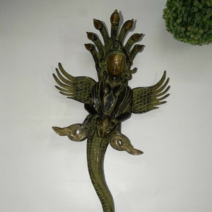 May include: A green and gold metal sculpture of a deity with multiple snake heads, wings, and a long snake tail.