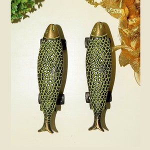 May include: A pair of fish-shaped cabinet pulls. The metal pulls feature a green and black scale design, with gold-colored heads and tail fins. Each pull is approximately 15 cm long.