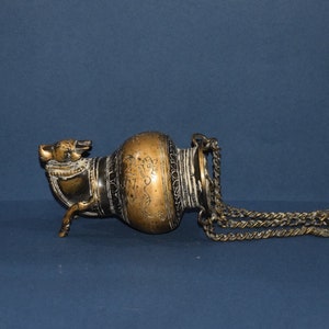 May include: A brass oil lamp with intricate carvings and a chain handle. The lamp is decorated with a stylised animal head and has three legs.
