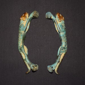 May include: A pair of antique brass door handles shaped like tigers. The handles are a teal blue color with gold accents.