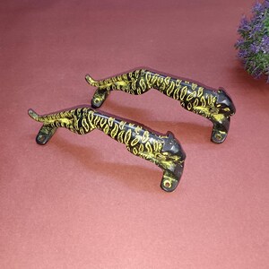 May include: Two black metal door handles shaped like running leopards with gold accents.