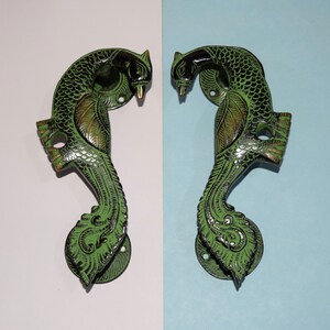 Może przedstawiać: Dwa zielone uchwyty do drzwi w kształcie pawia z misternymi detalami. Uchwyty są wykonane z mosiądzu i mają tradycyjny indyjski wzór.