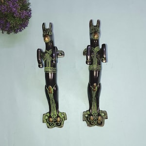 May include: A pair of antique-style door handles made of brass. The handles are shaped like horses with green and gold accents.