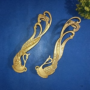 May include: Two ornate gold-toned metal door handles shaped like peacocks with intricate details.