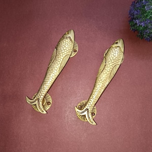 May include: Two gold-toned fish-shaped door handles. The handles are detailed with scales and fins.