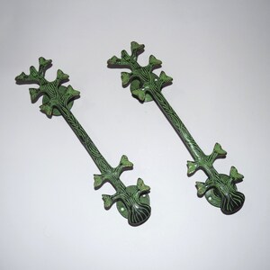 May include: Two green and black metal door pulls shaped like stylised trees with leaves.