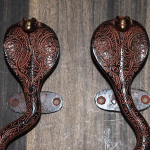 May include: A pair of ornate black and red metal door handles shaped like cobras with intricate floral designs.