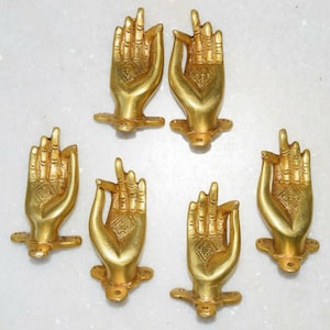 May include: Six gold-coloured metal hand-shaped door handles with intricate designs. The handles are in a variety of positions, some with fingers extended and others with fingers curled.