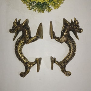 May include: A pair of ornate brass door handles shaped like dragons. The handles are detailed with scales and have a curled tail.