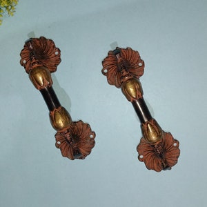 May include: Two ornate door handles with a black and gold finish. The handles have a decorative floral design.