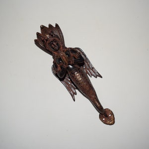 Può includere: Una maniglia per porta decorativa in ottone con un design dettagliato di una creatura mitologica con ali e un busto umano. La maniglia è rifinita in un colore marrone scuro con accenti dorati.