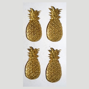 Op de afbeelding: Vier gouden ananasvormige ornamenten. De ananas zijn gedetailleerd met een textuur en hebben een realistische uitstraling.