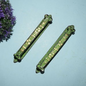 Puede incluir: Dos tiradores de cajón de metal verde con detalles dorados y diseños ornamentados. Los tiradores miden aproximadamente 12,5 cm de largo.
