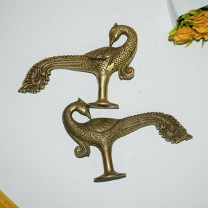 May include: Two ornate brass peacock door handles with intricate details. The handles are in the shape of peacocks with their tails spread out.