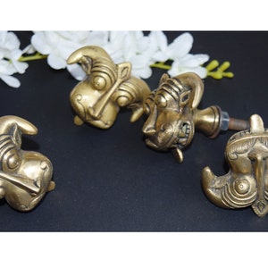 May include: Four ornate brass door knobs with animal faces. The knobs are detailed with intricate carvings and have a golden finish.
