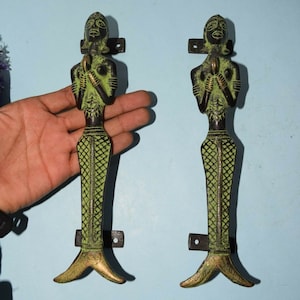 Può includere: Un paio di maniglie per porte decorative in ottone con una patina verde. Le maniglie hanno la forma di donne con le mani giunte in preghiera. Le maniglie hanno un design dettagliato e sono un'aggiunta unica a qualsiasi casa.