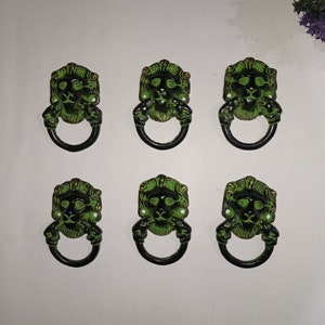 Könnte beinhalten: Sechs grüne und schwarze Schubladenknöpfe mit Löwenkopf und Ringgriff.