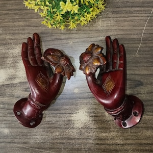 May include: A pair of ornate, red-brown, hand-shaped door pulls with gold accents. Each pull features a stylized flower design.