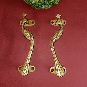 May include: A pair of gold peacock door handles with intricate details. The handles are shaped like peacocks with their tails spread out.
