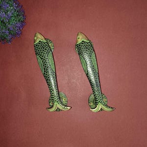 May include: A pair of green and gold fish-shaped door handles. The handles are made of metal and have a detailed design.