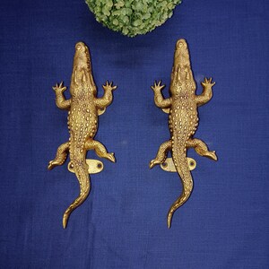 Op de afbeelding: Twee goudkleurige alligator deurgrepen. De grepen zijn gedetailleerd met textuur schubben en hebben een realistisch alligator ontwerp.