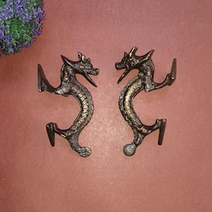 Puede incluir: Un par de tiradores de puerta de dragón de bronce antiguo. Los dragones se miran y tienen detalles intrincados.