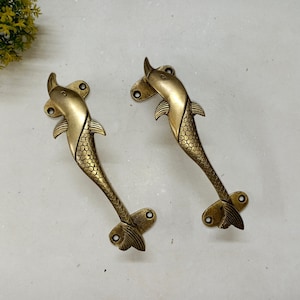 May include: Two gold-toned dolphin-shaped door handles. The handles are detailed with scales and fins.