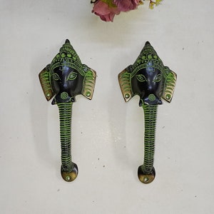 Könnte beinhalten: Ein Paar grüne und schwarze Metall-Türgriffe mit einem Elefantenkopf-Design. Die Griffe sind verziert und weisen komplizierte Details auf.