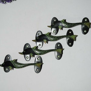 Könnte beinhalten: Satz mit vier schwarzen und grünen Delfin-Türgriffen. Jeder Griff hat ein detailliertes Delfin-Design mit einem grün-schwarzen Muster.