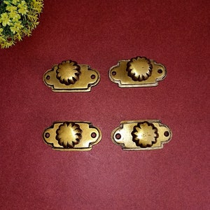 Puede incluir: Cuatro tiradores de cajón de latón antiguo con un diseño floral. Cada tirador tiene un pomo redondo con un patrón floral en relieve y una base rectangular.