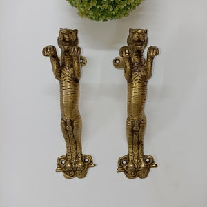 May include: A pair of gold-toned tiger-shaped door handles. The handles are detailed with tiger stripes and have a raised paw design at the bottom.
