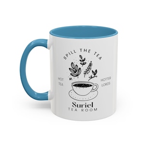 Pode incluir: Caneca de cer&acirc;mica branca com borda e al&ccedil;a azuis. A caneca apresenta uma ilustra&ccedil;&atilde;o em preto e branco de uma x&iacute;cara de ch&aacute; com vapor e folhas, com o texto "Spill the Tea, Hot Tea, Hotter Lords, Suriel Tea Room".