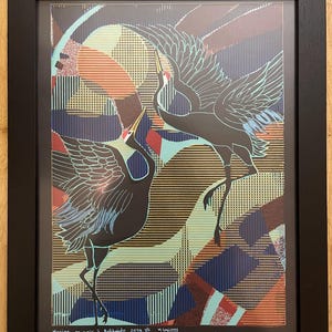 Op de afbeelding: Een ingelijste print van een zwart-witte illustratie van twee kraanvogels in vlucht tegen een kleurrijke geometrische achtergrond. De print is getiteld "mariage en noir" en gesigneerd "Hokkaido 2024 1/2" en "n.ogawa".