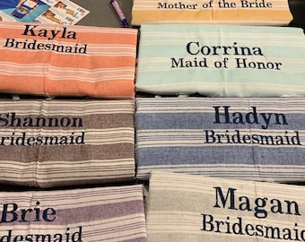 Può includere: Sei asciugamani a righe con nomi e titoli ricamati, tra cui "Momma P Madre della Sposa", "Kayla Damigella d'onore", "Corrina Damigella d'onore", "Shannon Damigella d'onore", "Hadyn Damigella d'onore" e "Magan Damigella d'onore".